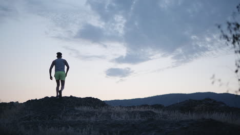 Slow-motion-trail-runner-reaches-mountain-summit-at-dawn,-fitness-concept