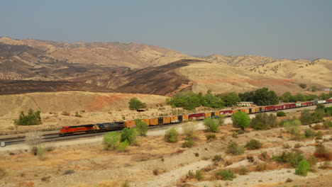 The-Union-Pacific-train-passes-by-landscape-scorched-by-wildfires-near-Caliente,-California---aerial-view