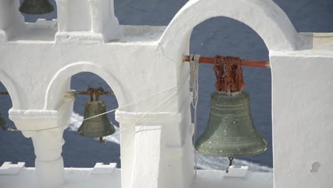 Ikonische-Kirchenglocken-In-Oia,-Santorini,-Griechenland,-Während-Ein-Boot-Vorbeifährt