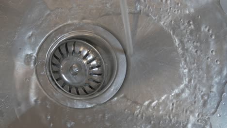 Running-tap-water-flowing-down-plug-hole-or-drain