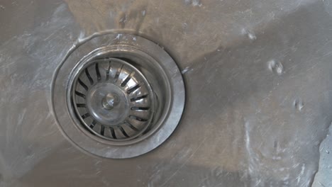 Running-tap-water-flowing-down-plug-hole-or-drain