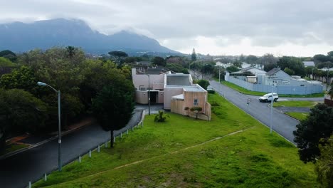 A-drone-shot-revealing-the-suburb-of-Meadowridge-in-Cape-Town,-with-mountains-and-mist-in-the-background