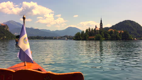 Beautiful,-calm,-relaxing-POV-from-Pletna-boat-on-Lake-Bled-in-Slovenia-with-view-of-Castle-and-Island-with-Assumption-of-Mary-church,-HD