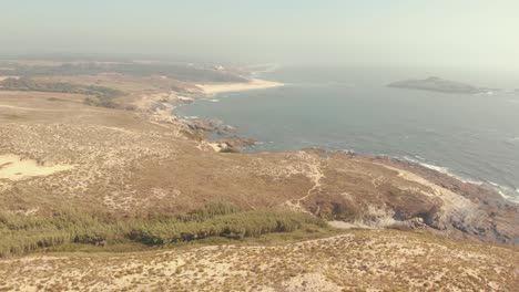 Flying-over-the-mainland,-away-from-the-ocean,-of-Porto-Covo-in-Portugal
