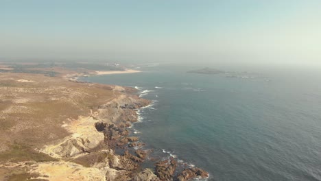 Flying-over-the-mainland,-towards-the-ocean,-of-Porto-Covo-in-Portugal