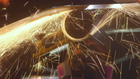 Industry-worker-files-metal-parts-with-a-circular-saw,-generating-spectacular-sparks