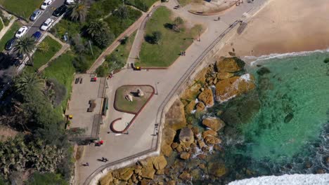 Top-Down-View-Of-Saltwater-Rock-Pool-And-Foamy-Waves-On-Sandy-Shore-Of-Bronte-Beach-In-Sydney,-Australia---aerial-drone-shot