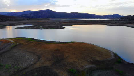 Aerial-drone-boom-down-over-dried-up-Irvine-Lake-in-Southern-California-at-beautiful-sunset--lake-is-almost-empty-due-to-drought