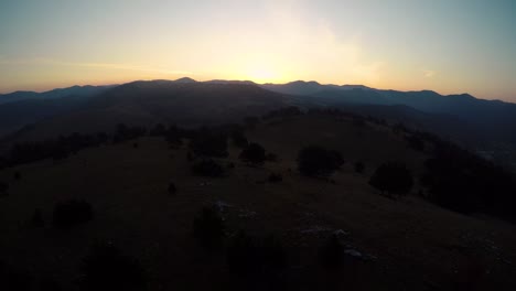 Fliegen-Einer-Drohne-Auf-Einem-Hügel-Mit-Blick-Auf-Die-Berge-Während-Des-Sonnenaufgangs