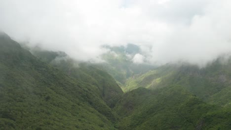 Impressive-wild-mountain-range-with-lush-greenery-on-slopes-covered-in-clouds