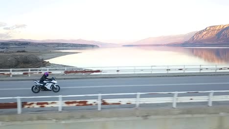 Drone-shot-of-a-girl-riding-a-super-sport-motorcycle-and-accelerating-on-a-bridge-over-a-lake-in-Greece