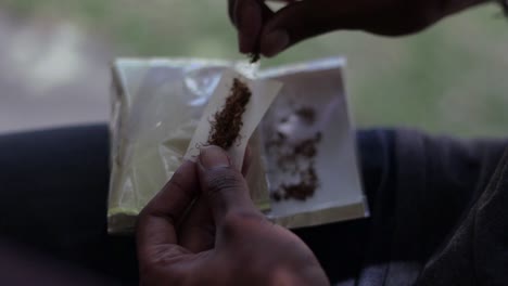 a-slow-motion-shot-oh-male-hands-preparing-tobacco-to-roll-into-a-cigarette