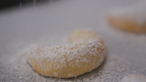 Close-up-of-freshly-baked-Vanilakipferl-cookies-as-powdered-sugar-sprinkles-down-on-top