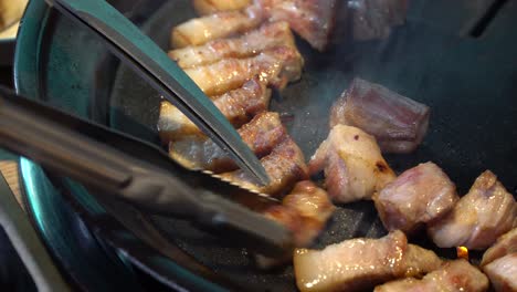 Close-up-of-fat-pork-belly-sizzling-on-traditional-Korean-grill