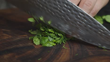 Cutting-herbs-ingredients-on-cut-board-with-big-kitchen-knife