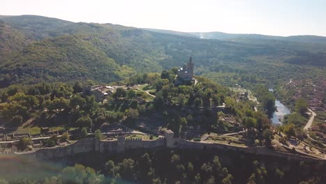 Panoramización,-Grúa-Hacia-Abajo,-Tiro-De-Drone-De-Una-Iglesia-En-Una-Colina-Con-Un-Sitio-Arqueológico-En-Veliko-Tarnovo