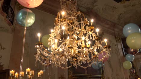 A-huge-old-chandelier,-surrounded-by-balloons-and-candles,-in-an-atmospheric-classic-wedding-party-location