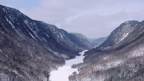 Epic-blue-hour-flight-over-snowy-fjord-in-wintertime-boreal-forest,-Parc-National-de-la-Jacques-Cartier,-Quebec,-Canada