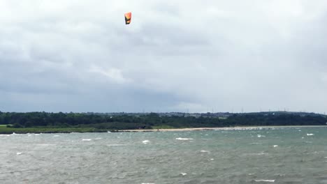 A-kite-surfer-jumping-20-feet-into-the-air-and-landing-with-style,-on-a-windy-summer-day-|-Portobello-beach,-Edinburgh-|-Shot-in-HD-at-cinematic-24-fps