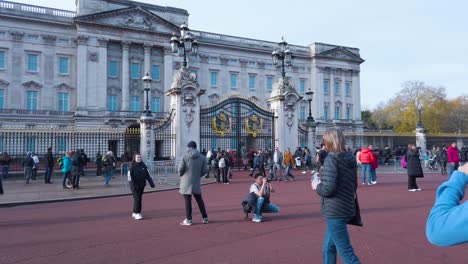 Pan-shot-form-left-to-right-up-of-locals-and-tourists-walking-in-front-of-Buckingham-Palace,-London,-UK-at-daytime
