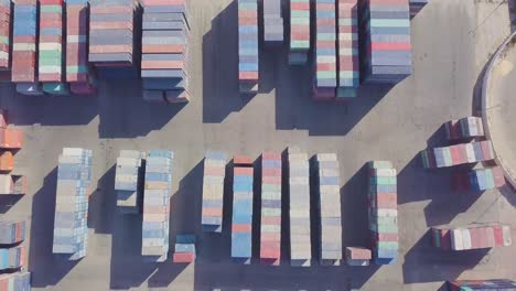 Birds-eye-view-of-a-flyover-a-very-large-container-yard-with-colorful-containers,-trucks,-forklifts,-and-container-loaders