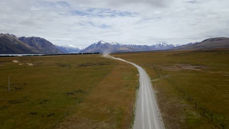 Dusty-dirt-road-with-fast-vehicle-approaching-in-southern-Alps-of-New-Zealand