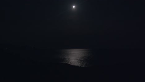 moon-and-moonlight-reflecting-over-sea-at-night,-extreme-long-shoot