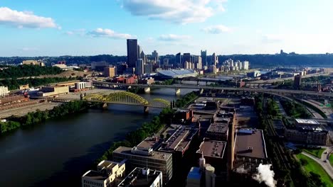 Drone-fly-over-aerial,-birds-eye-shot-flying-towards-David-McCullough,-16th-street-bridge-and-industrial-factories-along-the-Allegheny-River-on-a-partly-cloudy-day-in-Pittsburgh,-Pennsylvania