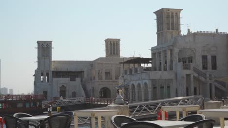 Waterfront-Buildings-With-Wind-Towers-In-Al-Fahidi-Historical-District,-Dubai,-UAE---sideways-shot
