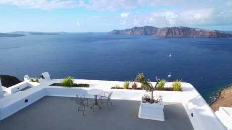 Table-with-2-chairs-on-a-terrace-in-Santorini,-view-of-the-volcano,-Aegean-sea