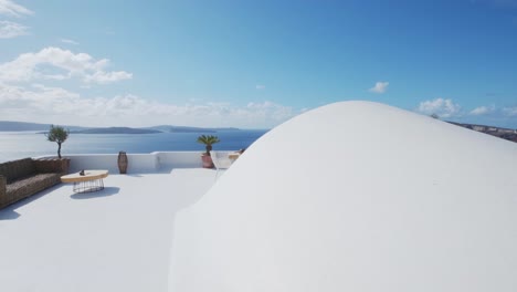 Idyllic-white-terrace-with-table-and-chairs,-with-a-view-of-the-volcano-and-Aegean-sea