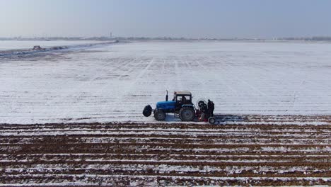 Blauer-Traktor,-Der-Das-Schneebedeckte-Feld-Zum-Pflanzen-In-Der-Ukraine-Bebaut