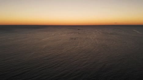 Drohne-Fliegt-über-Dem-Meer-Und-Ein-Boot-Im-Hintergrund