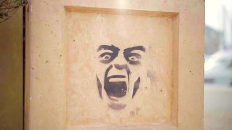 Street-art-on-a-wall,-graffiti-of-a-screaming-face,-symbol-of-frustration-and-anger