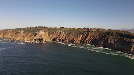 Drone-shot-flying-towards-a-rocky-cliff-on-the-edge-of-the-ocean