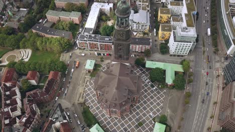 flying-above-a-church-in-hamburg-city-germany,-gaining-hight,-tilting-camera-down