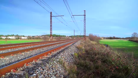 Empty-and-quiet-railroad-in-the-countryside,-no-train-passing-by-on-a-sunny-day-with-blue-sky
