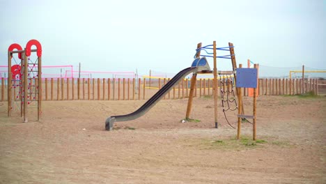 Empty-playground-at-the-beach,-no-children-playing,-deserted-during-the-Covid-19-pandemic-lockdown,-on-a-cloudy-day