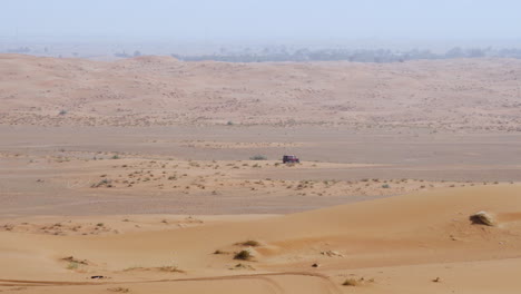 Four-Wheel-Landcruiser-Driving-In-Arid-Desert-During-Daytime-In-Sharjah,-United-Arab-Emirates---Tracking-Shot