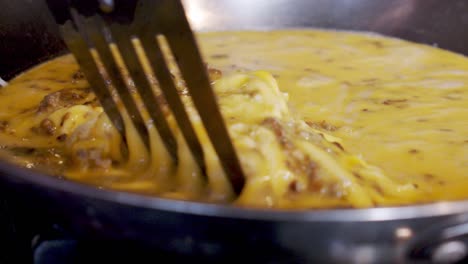 Wide-shot-cooking-sausage-eggs-in-pan-on-stovetop-in-slow-motion