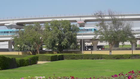 Dubai-Metro-Train-With-Traffic-On-Highway-From-Empty-Park-Of-Al-Rashidiya-In-Dubai,-United-Arab-Emirates
