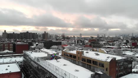 Combing-the-rooftops-of-Brooklyn,-NY's-East-Williamsburg,-this-aerial-shot-explores-the-skies-right-after-a-large-snow-storm
