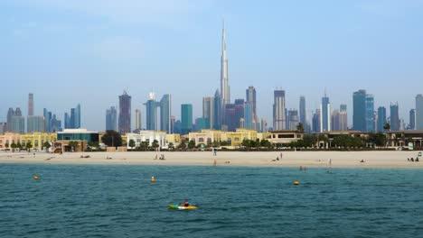 Steady-pullout-shot-of-the-iconic-Dubai-skyline-and-people-enjoying-a-day-of-leisure-at-the-beach