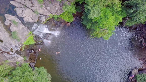 waterfall-and-its-pond,-shot-is-taken-by-drone-where-the-drone-is-rotated-around-its-axis-with-a-bird's-eye-view-of-the-pond