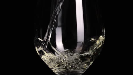 Pouring-delicious-white-wine-into-wineglass-isolated-on-black-background