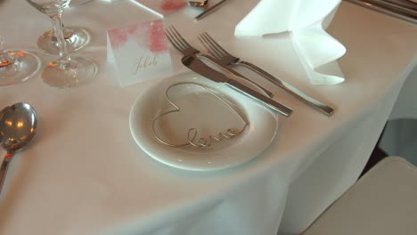 Weiße-Tischdecke-Mit-Namenskarte-Und-Herzform-In-Weißer-Platte-Bei-Festlichen-Hochzeiten