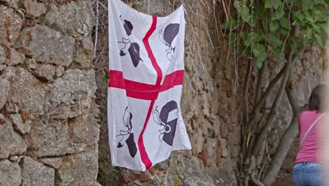 Beautiful-white-and-red-flag-of-Sardinia-waving-on-side-of-stone-wall,-close-up-view