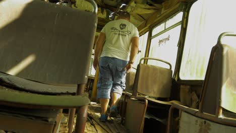 Lost-person-walking-through-interior-of-abandoned-school-bus,-static-view