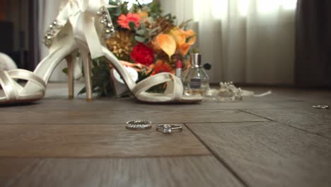 Bridge-accessories-and-wedding-ring-spinning-on-wooden-floor,-close-up-shot
