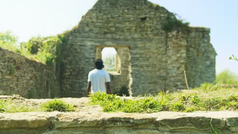 4K-footage-of-black-man-walking-out-of-old-church-ruins-in-England